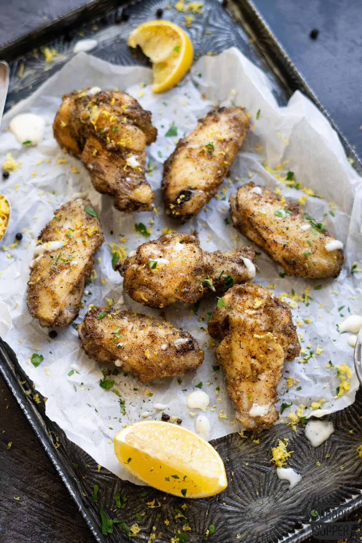 air fryer wings on a baking tray with lemon wedges