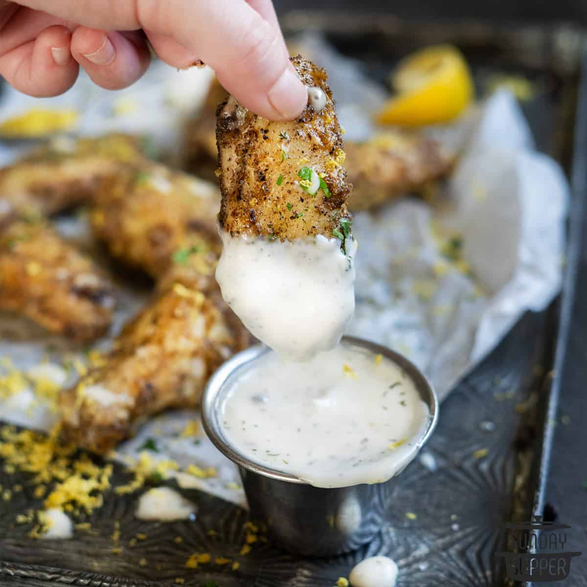dipping an air fryer chicken wing in sauce up close
