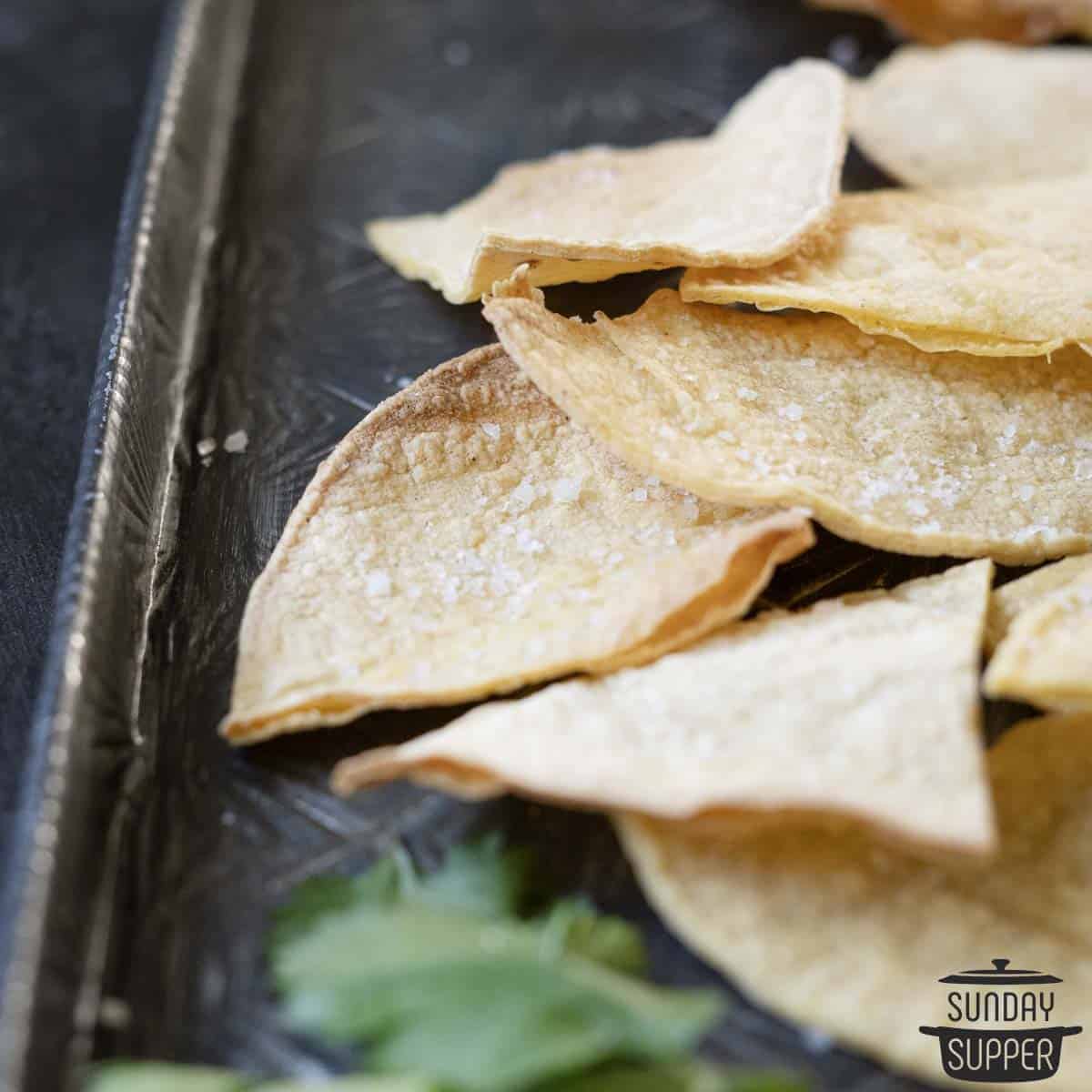 salty homemade tortilla chips up close on black platter