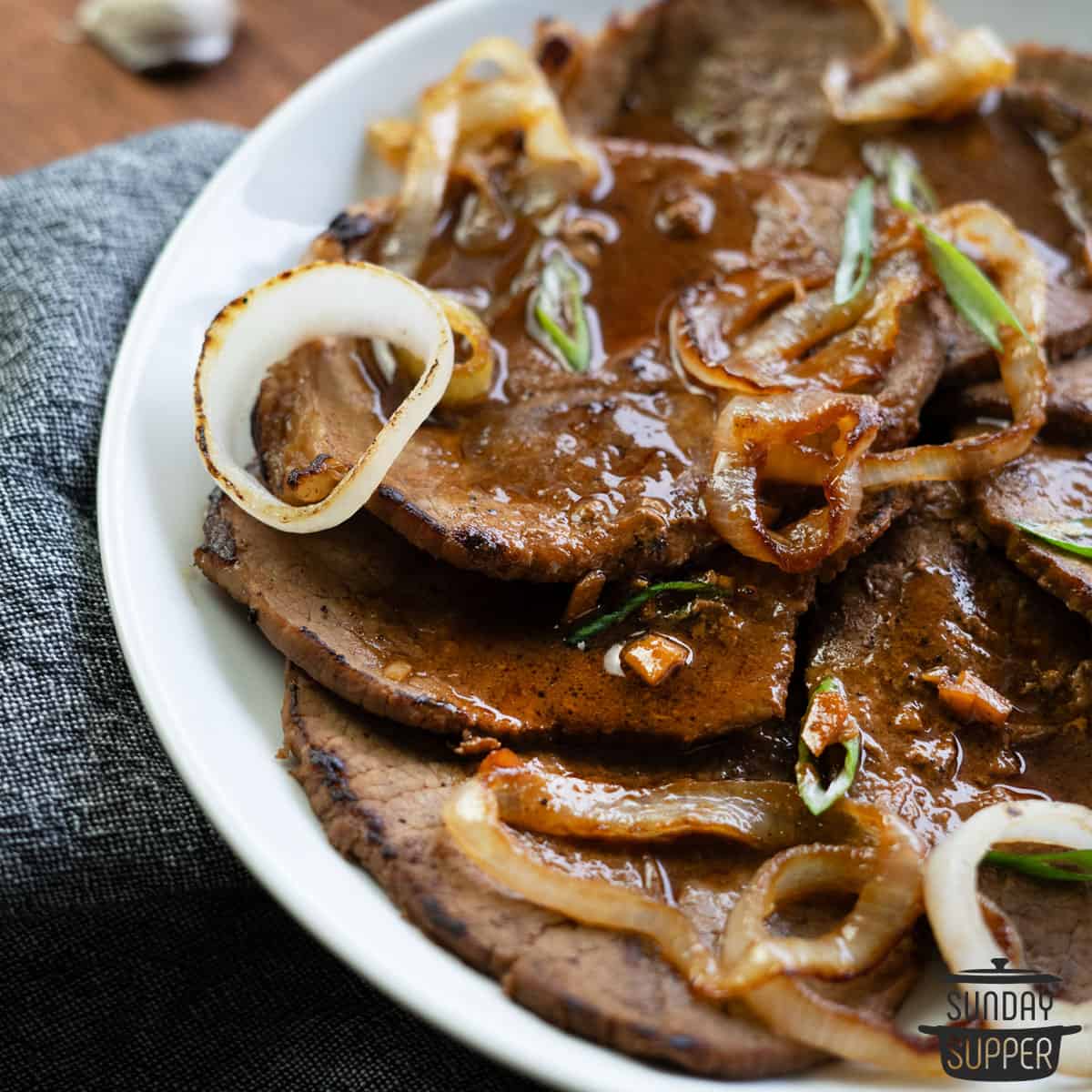 a plate of bistek with onions and gravy