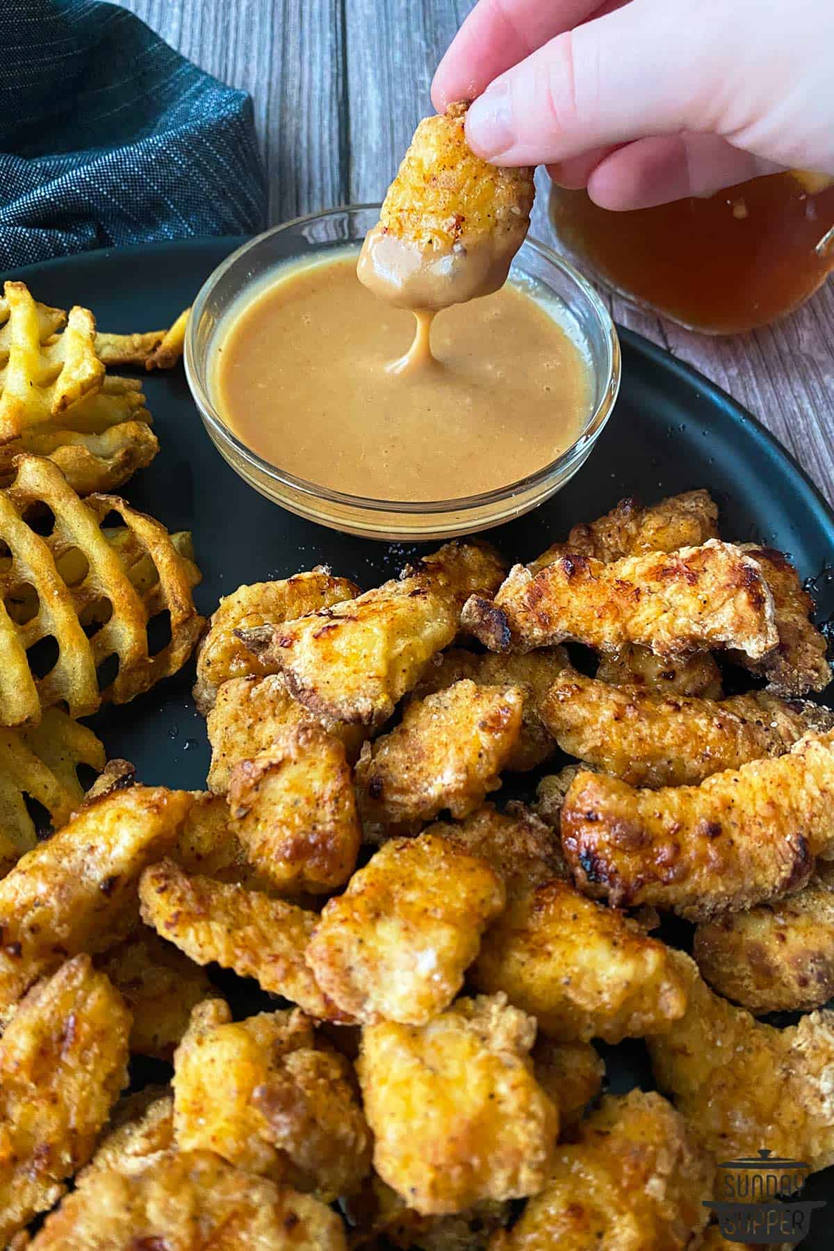 a platter of waffle fries and nuggets with a bowl of dipping sauce