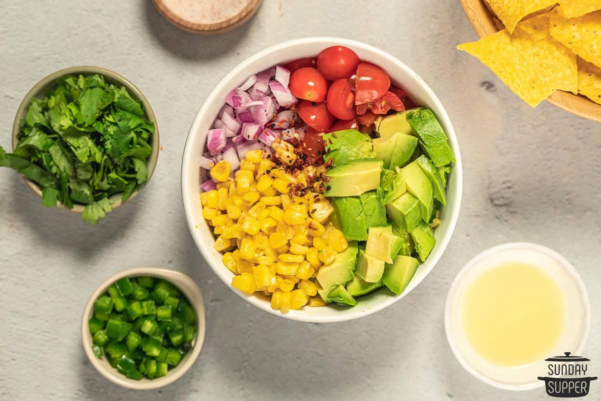 all the ingredients for chunky guacamole ready to be mixed in a bowl