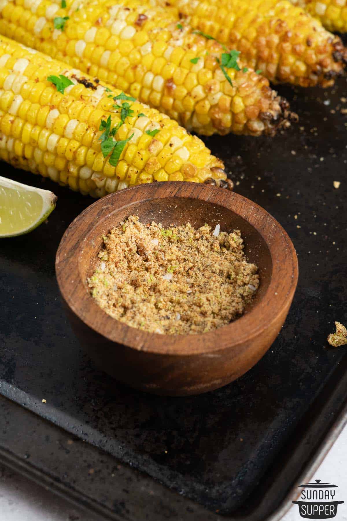 corn seasoning in a small bowl next to roasted corn on the cob