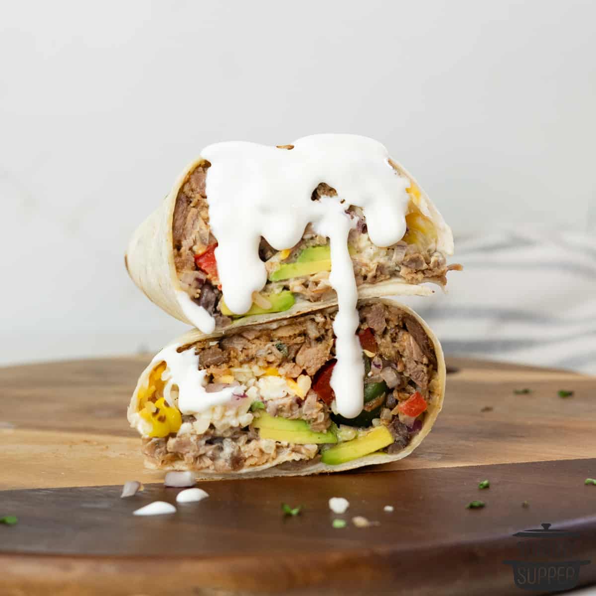 a stacked set of burritos with crema