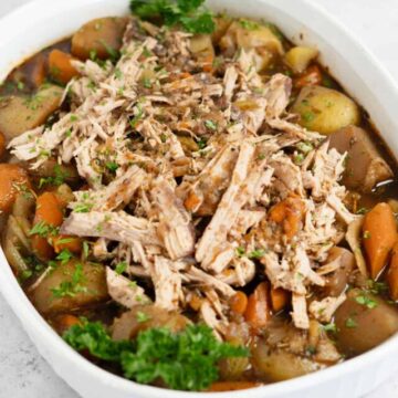 shredded pork pot roast in a serving bowl with vegetables and gravy