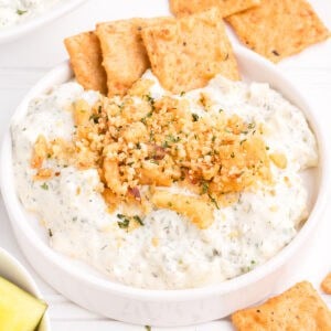 fried pickle dip in a white bowl with crackers for serving
