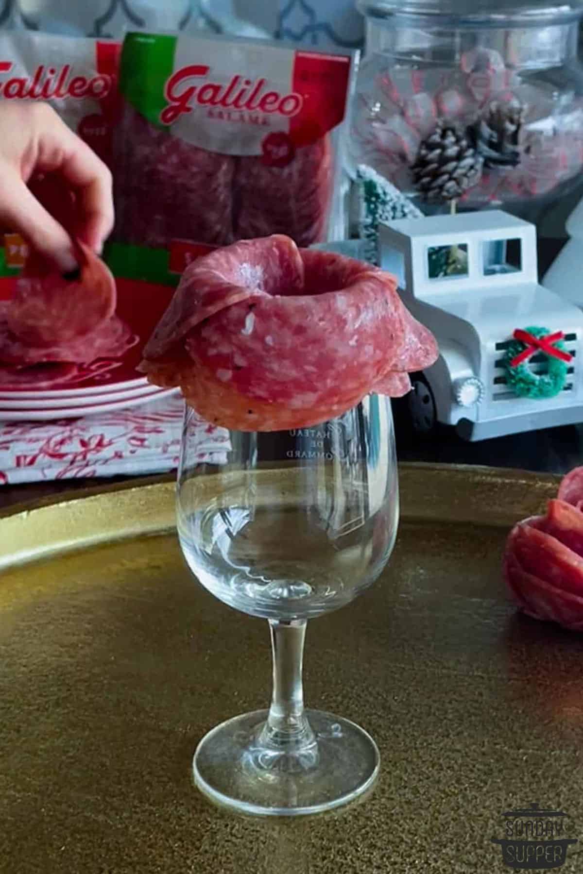 salami being layered over the rim of a glass