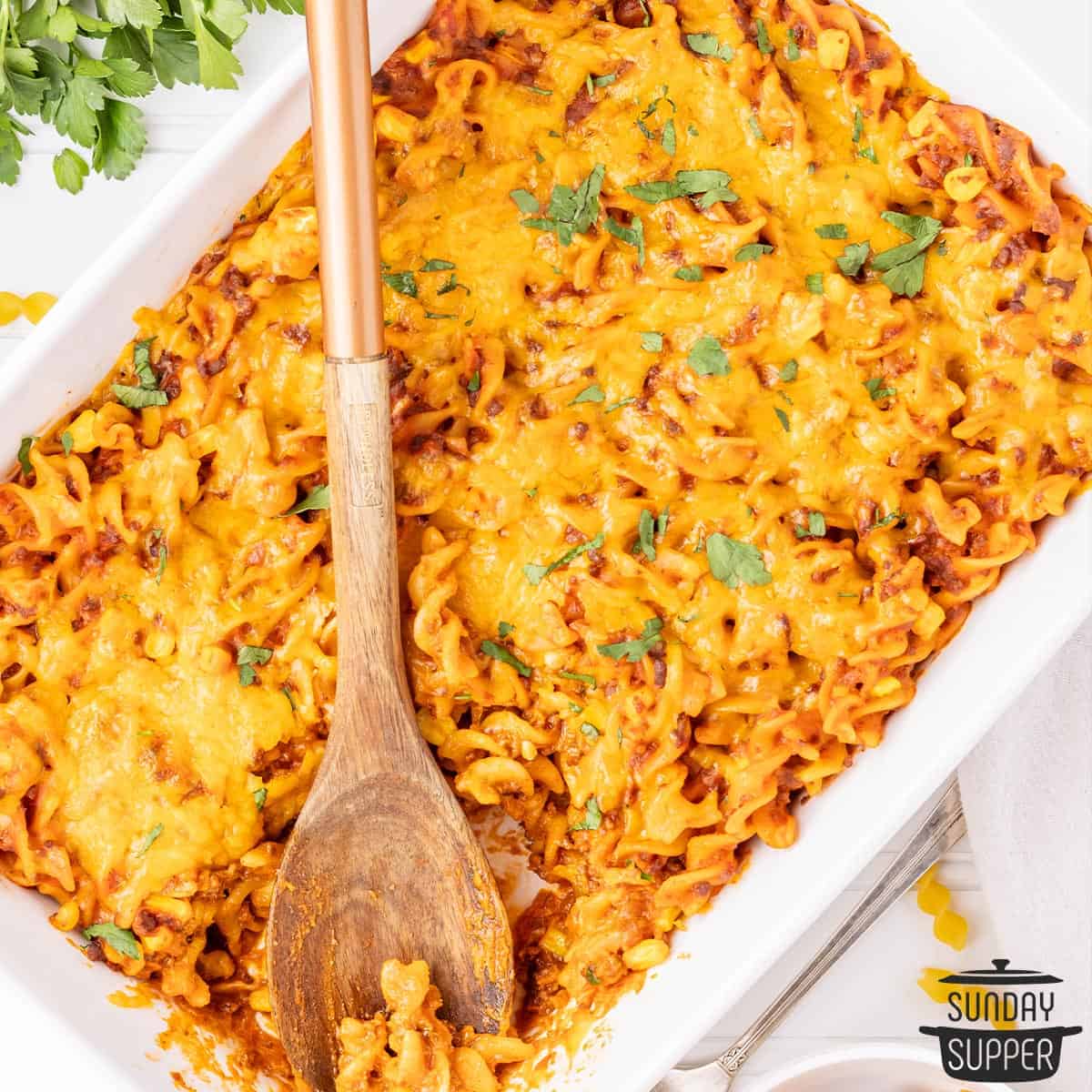 sloppy Joe casserole in a white baking dish with a wooden spoon inside