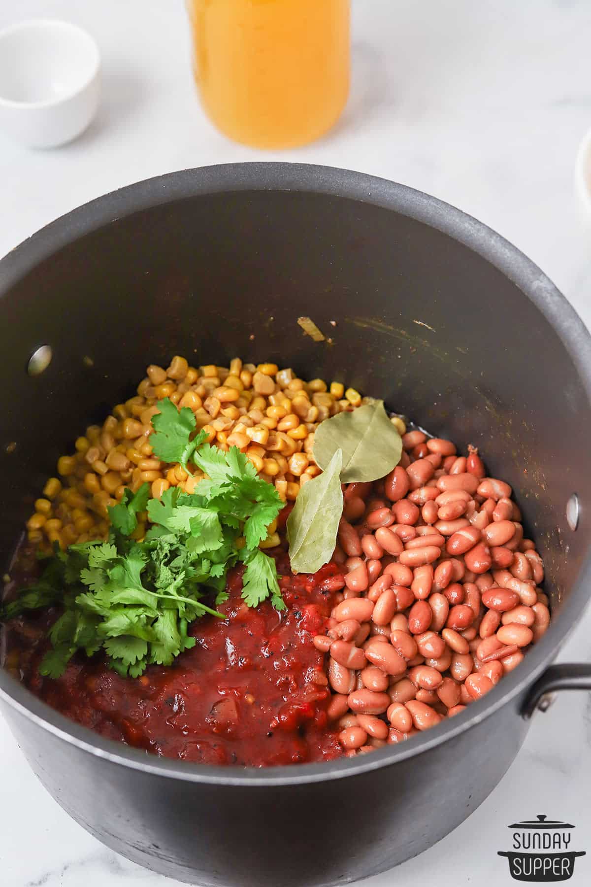 the beans, corn, tomatoes, bay leaves, and cilantro added to the pot