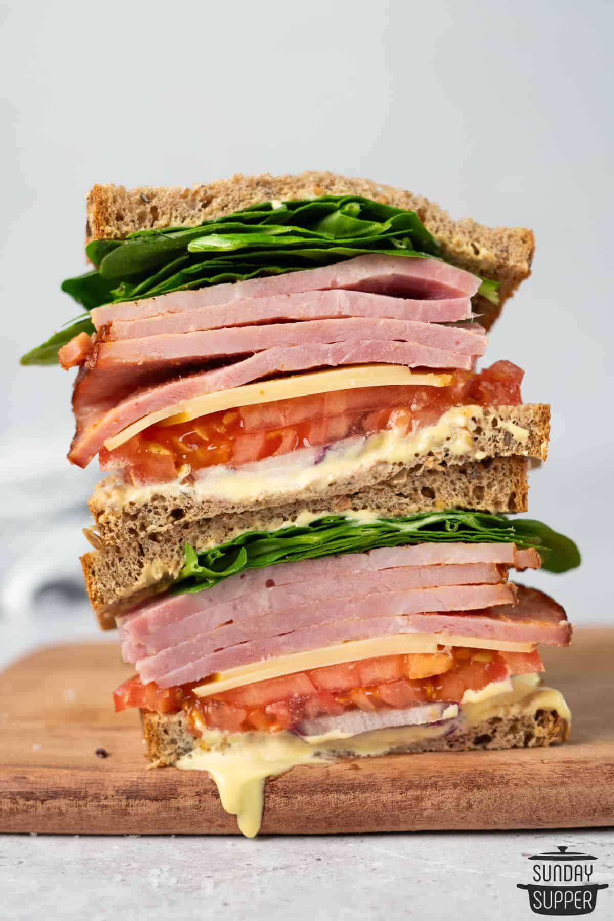 a stack of ham sandwiches sliced in half to show the toppings