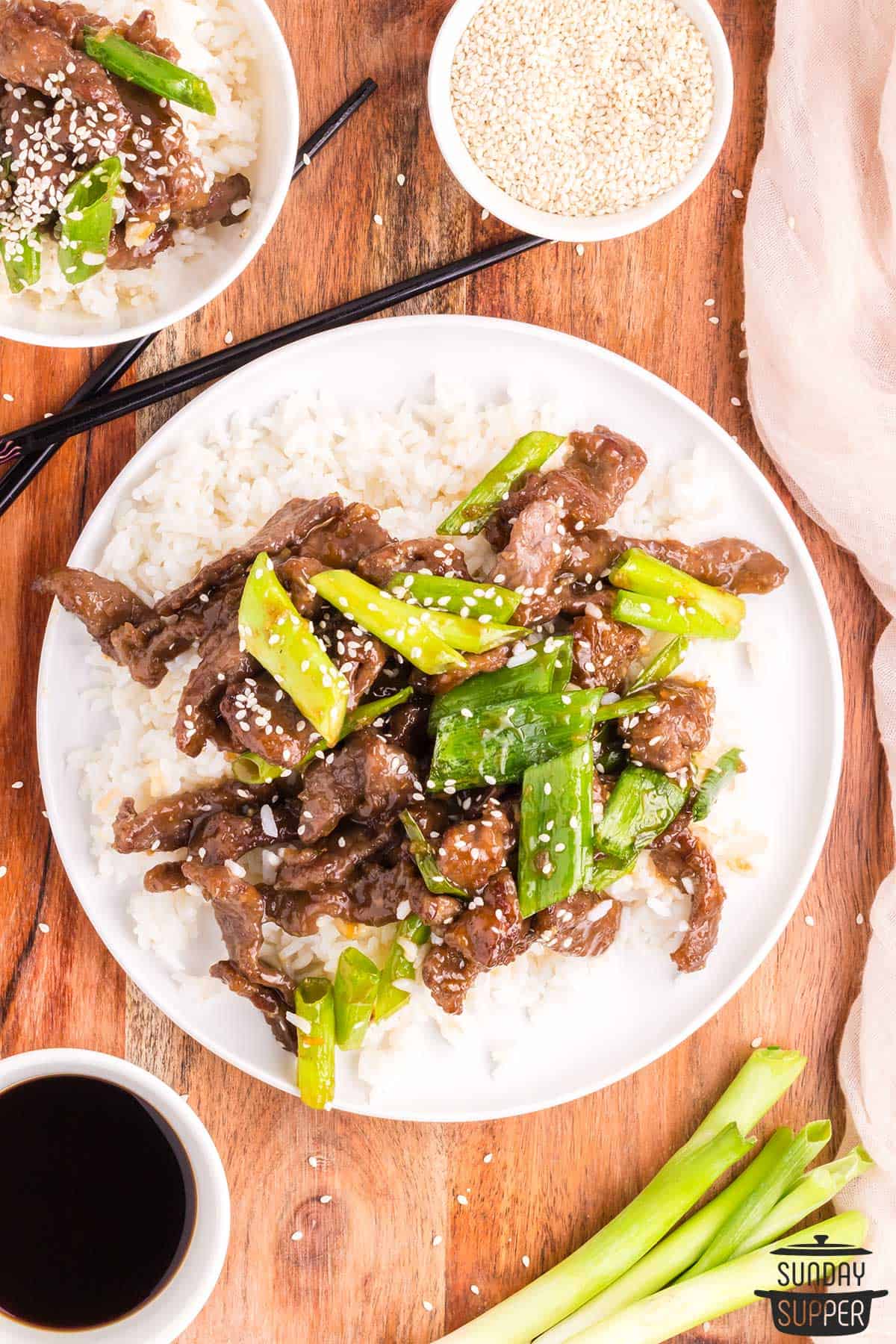 a plate of rice and mongolian beef with extra green onions and sesame seeds