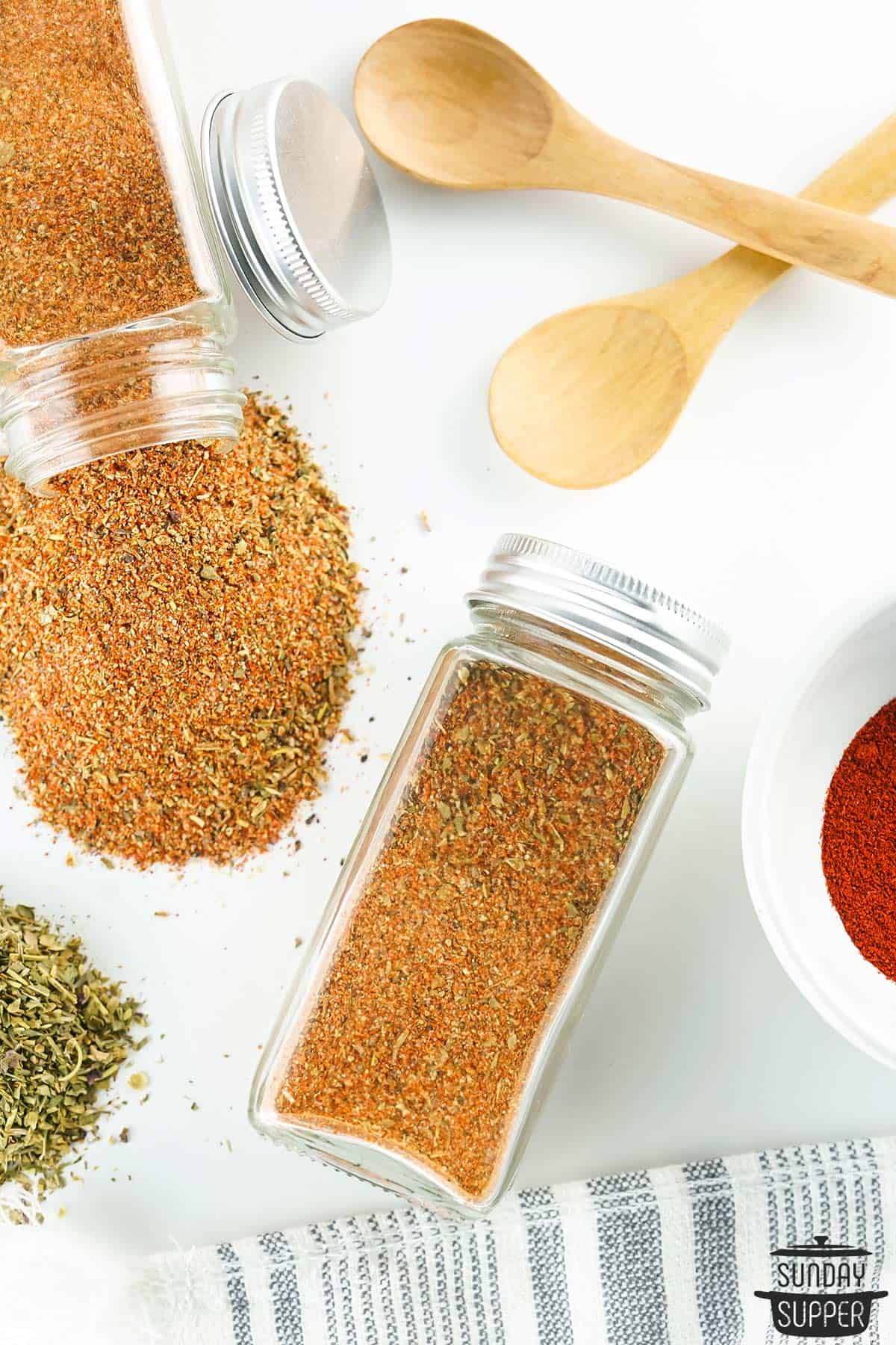 two spice jars filled with cajun seasoning, with one spilled