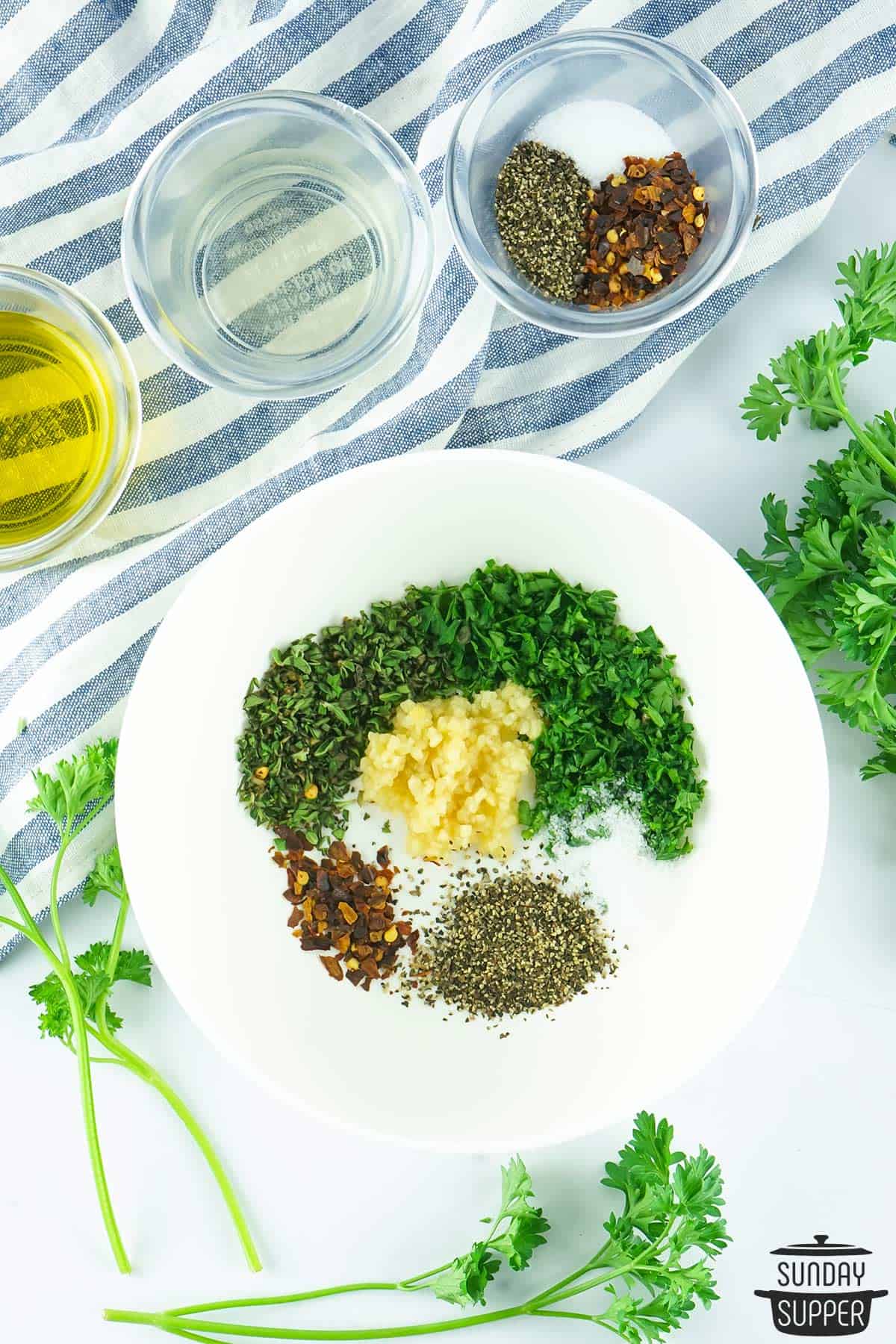 chimichurri ingredients added to a bowl to mix