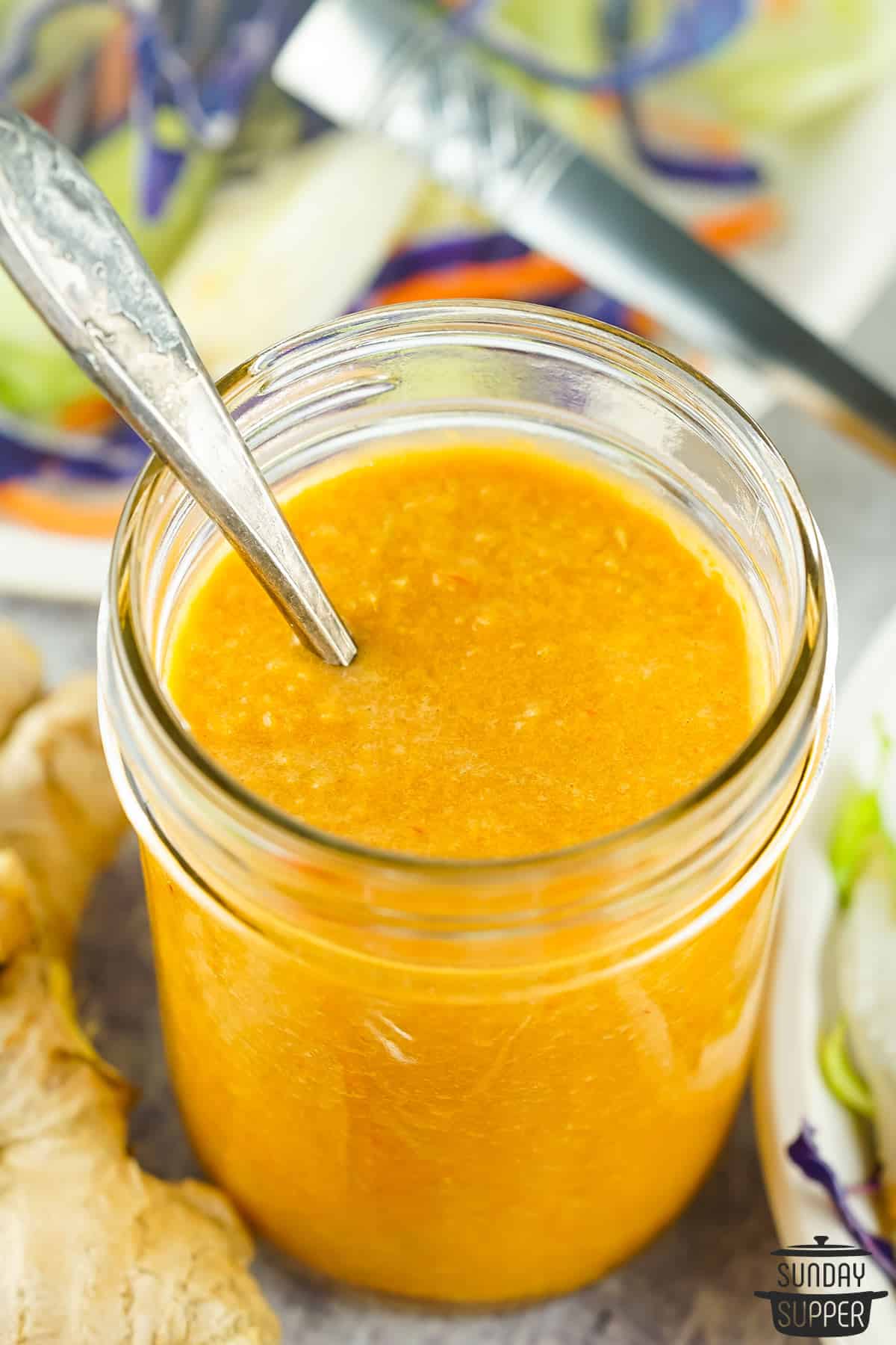 a spoon in a jar of fresh ginger dressing