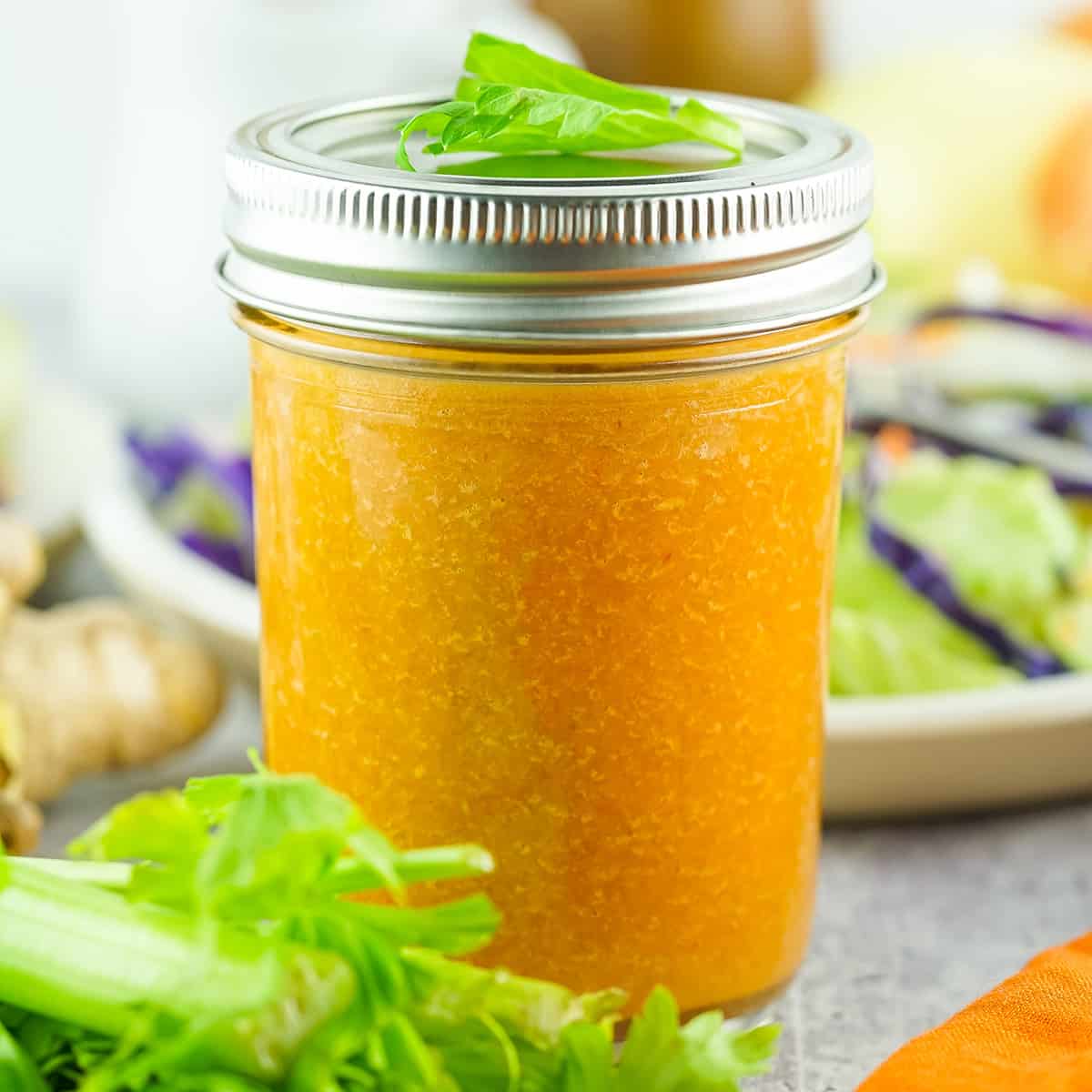 a bottled jar of ginger dressing next to lettuce