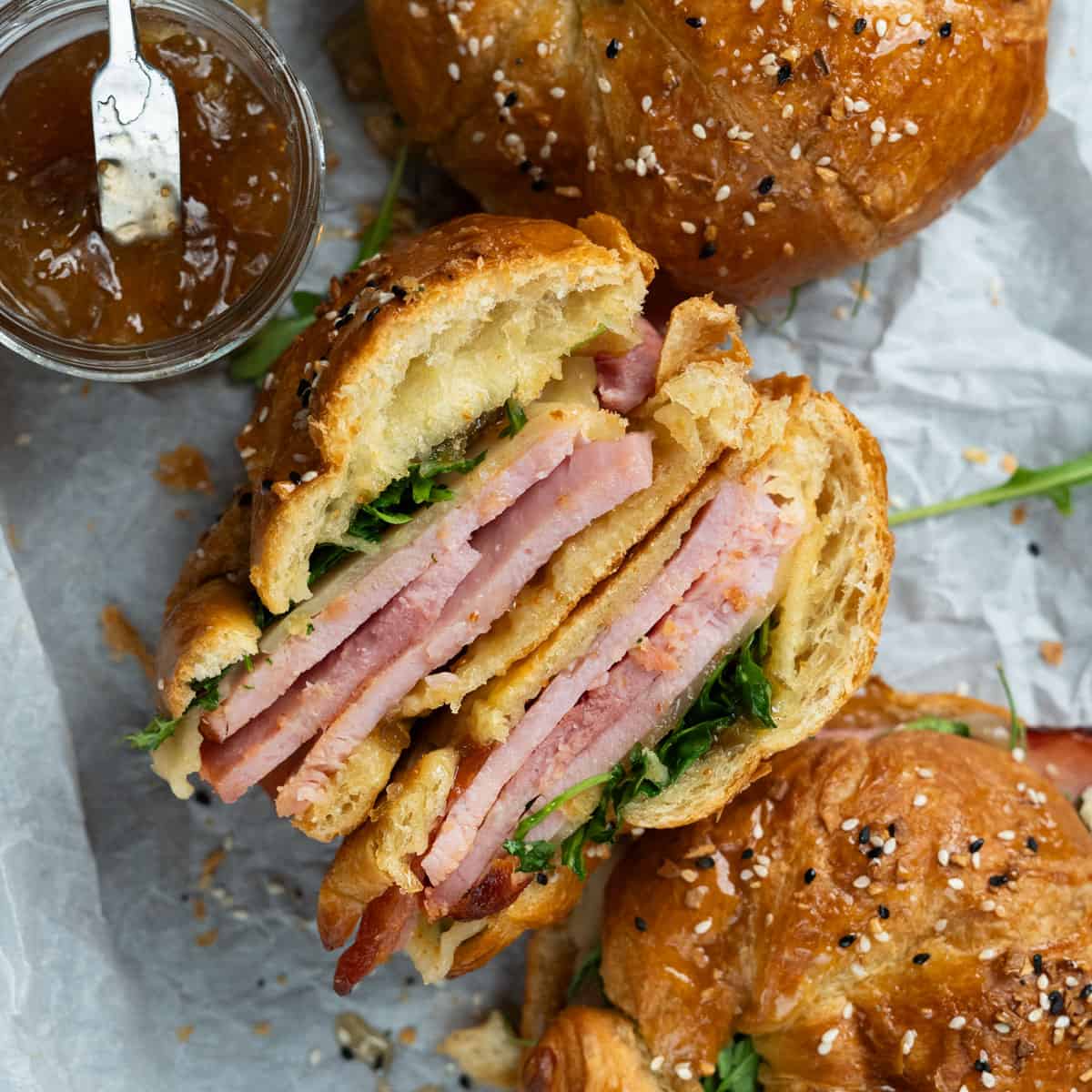 ham and cheese croissant sliced in half with jam on the side