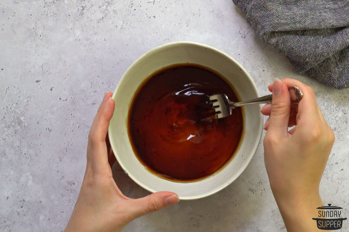 the honey, soy sauce, and vinegar being mixed in a bowl with a fork