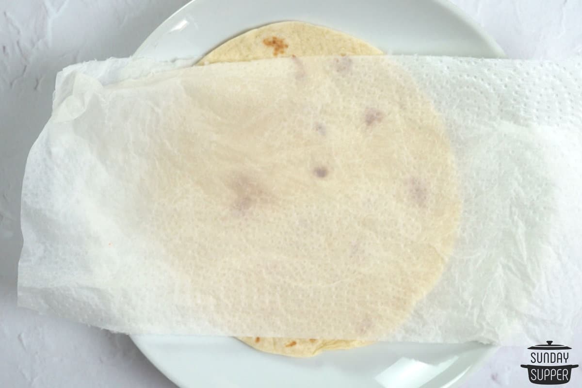 a tortilla on a plate with damp paper towel on top
