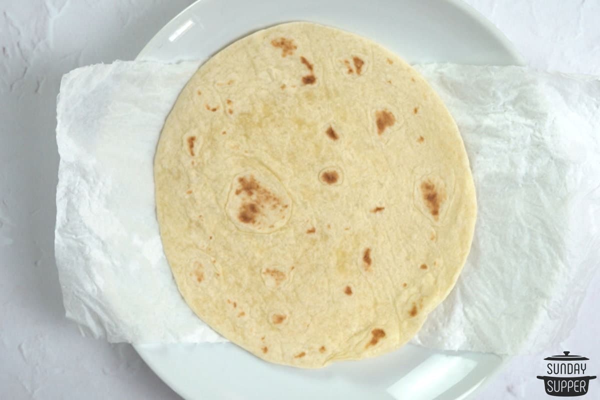 a tortilla on a plate placed on top of a damp paper towel