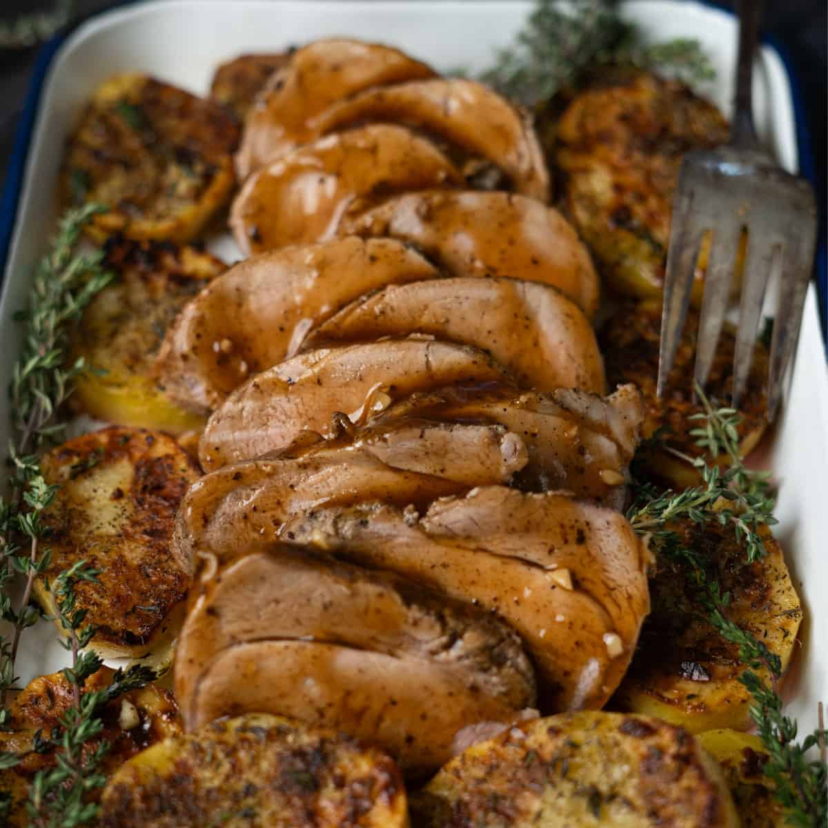 sliced instant pot pork tenderloin on a white tray with gravy served on top