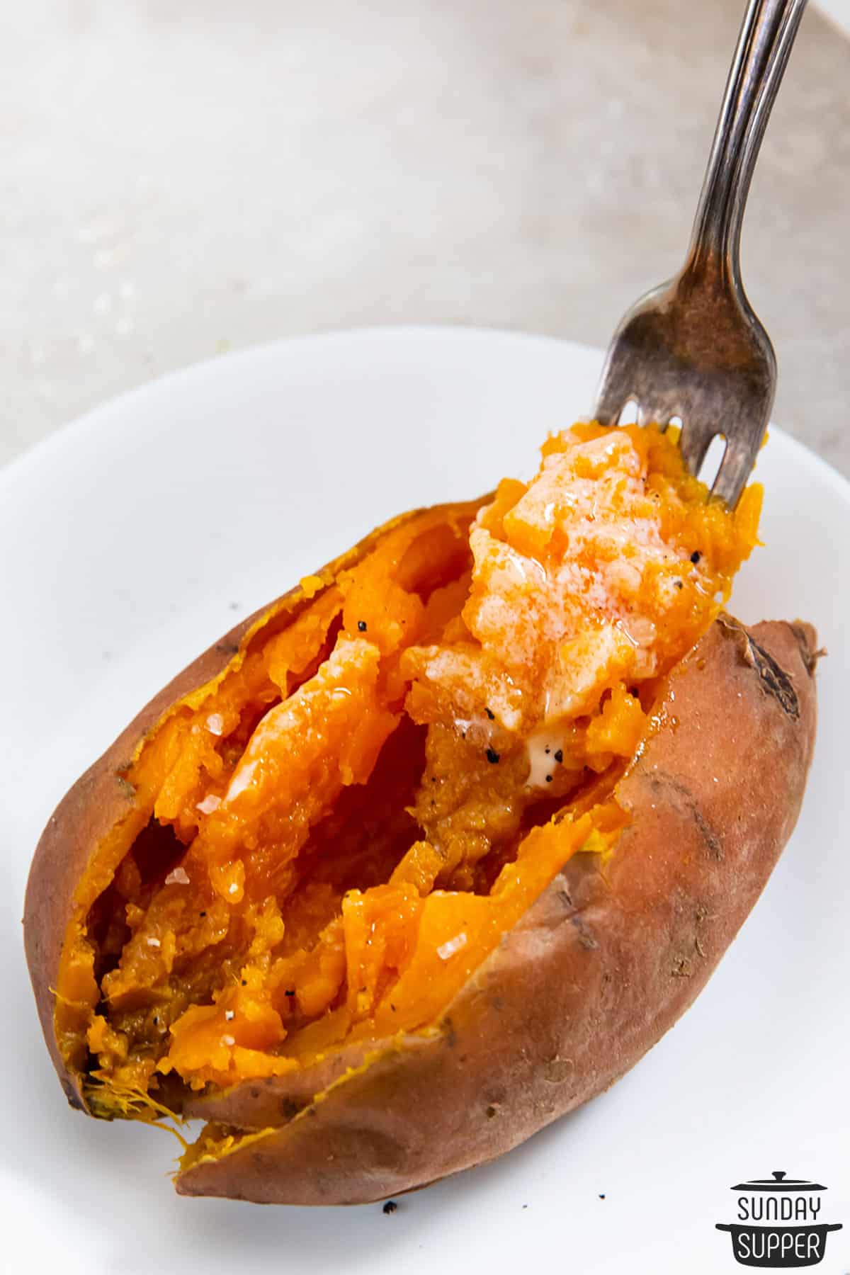 a fork digging flesh out of a sweet potato