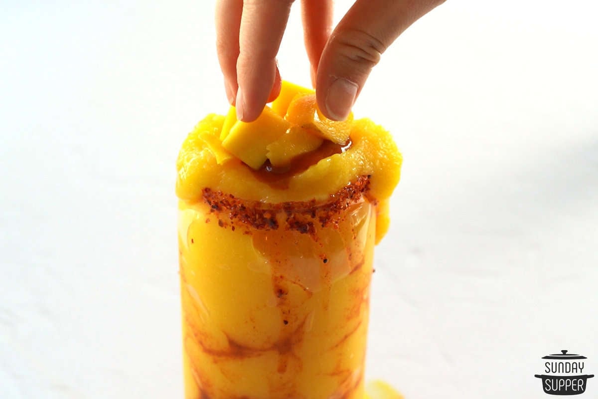 adding fresh mango on top of mangonadas
