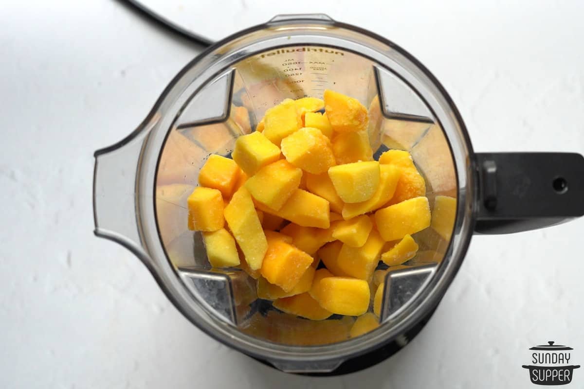 adding frozen mango in the blender