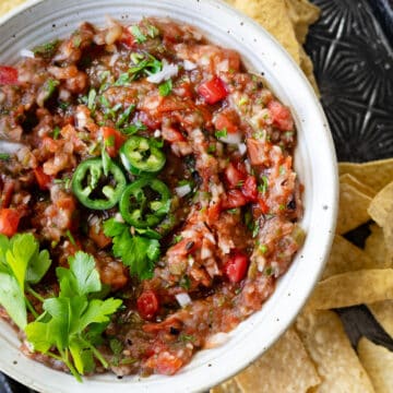 close up of fresh tomato salsa in a bowl with cilantro and jalapeno slices