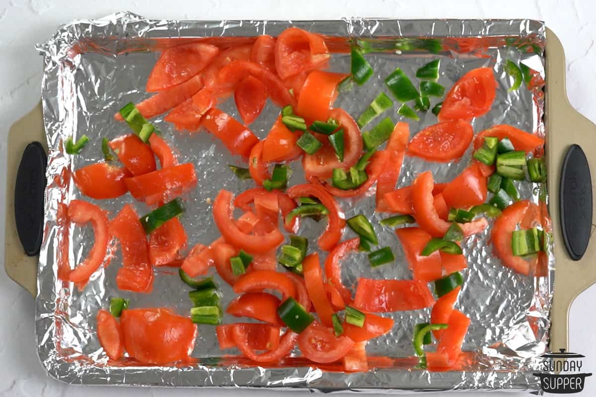 peppers and jalapenos on a foil-lined baking sheet