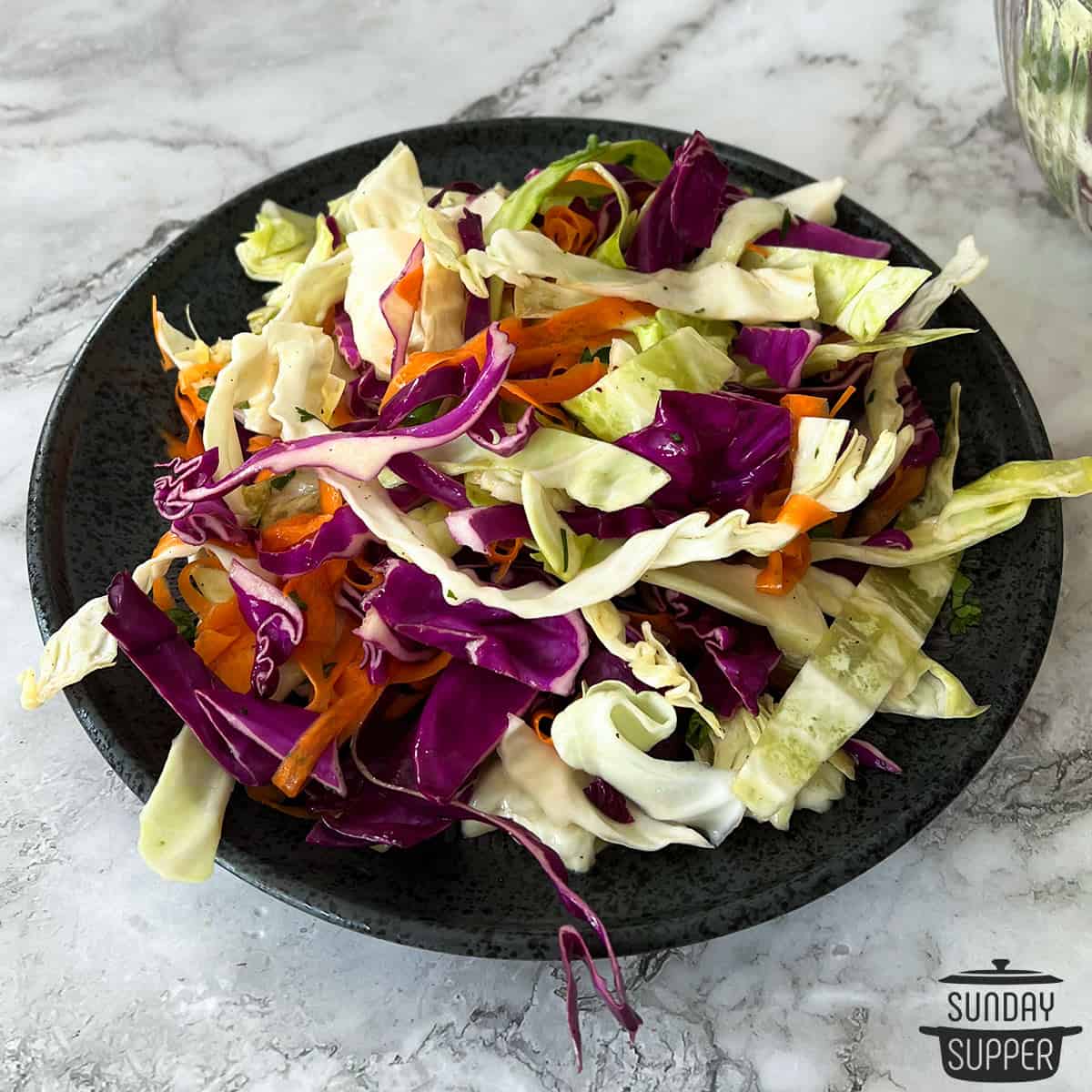 a black plate filled with asian cabbage slaw