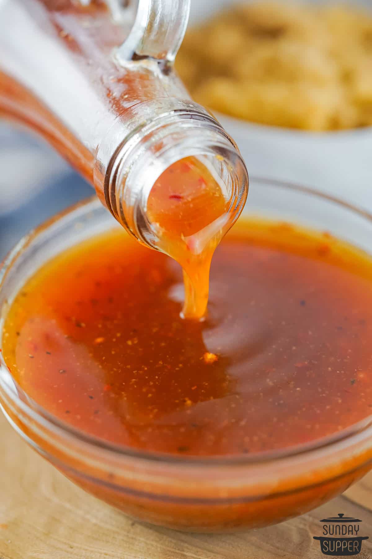completed hot sauce being poured from a glass jar into a bowl