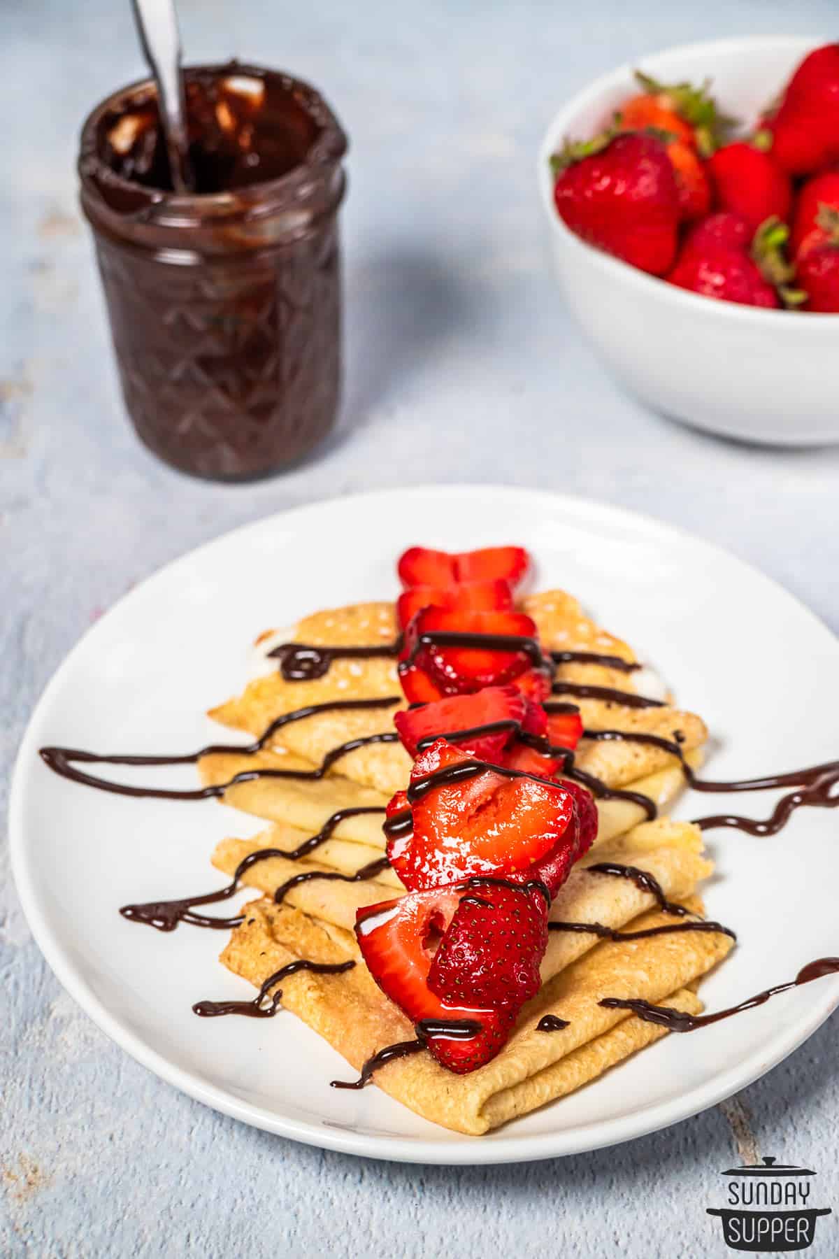 chocolate sauce drizzled over crepes with strawberries