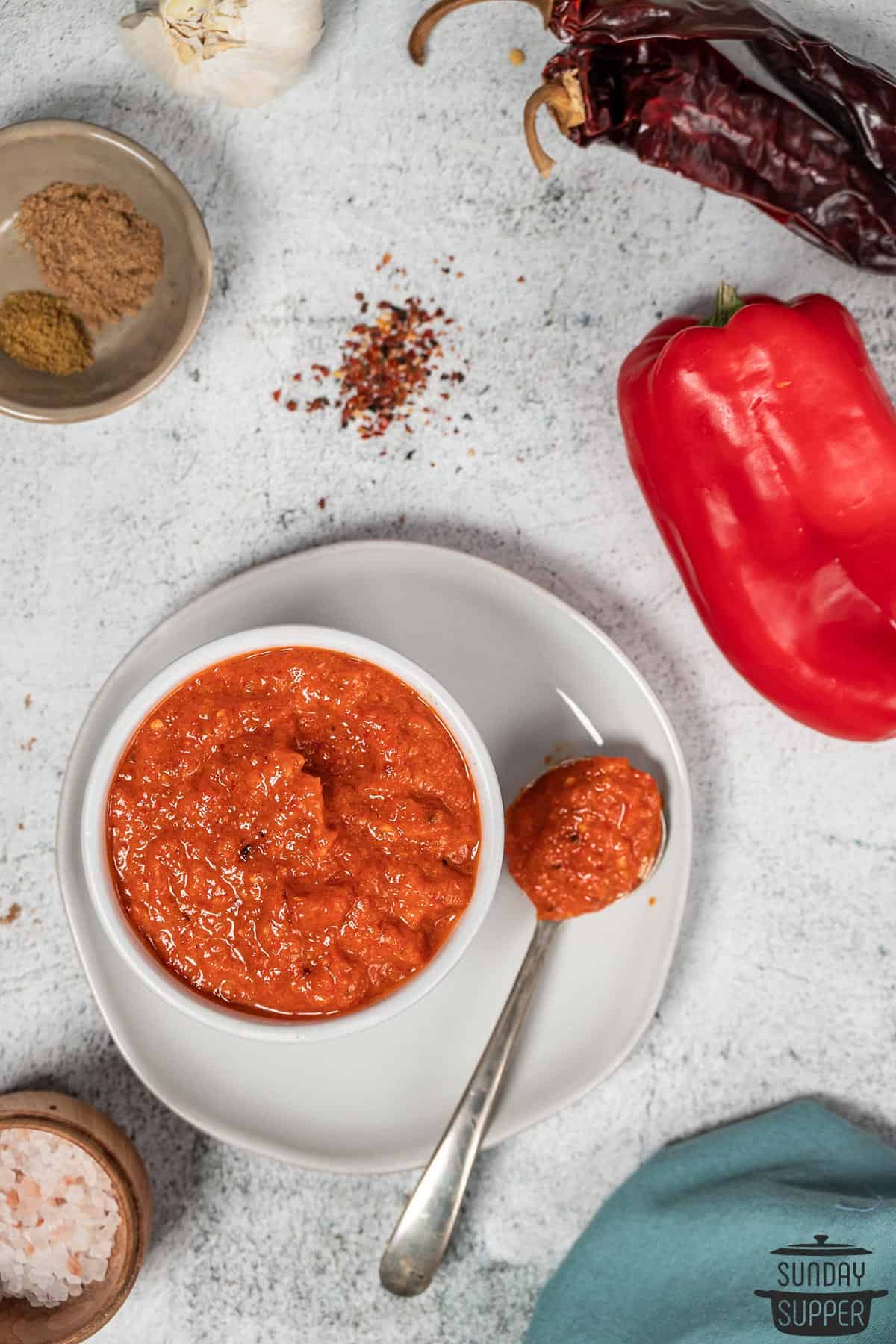 a bowl of harissa sauce with extra ingredients around it