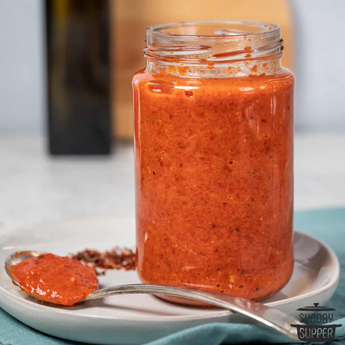 a closeup of a jar of harissa sauce and a spoon full of harissa