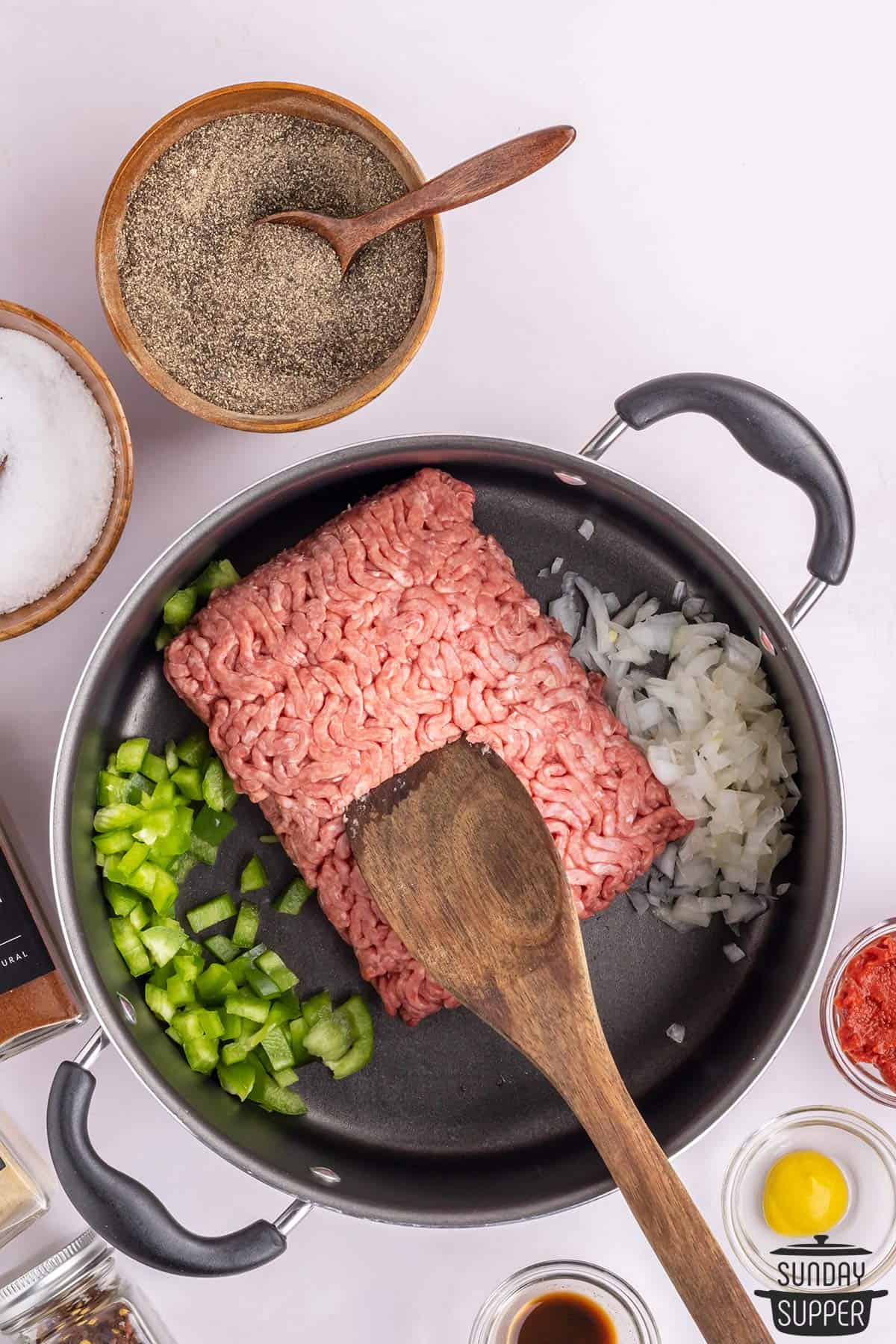 the ground meat, onions, and peppers added to a pan