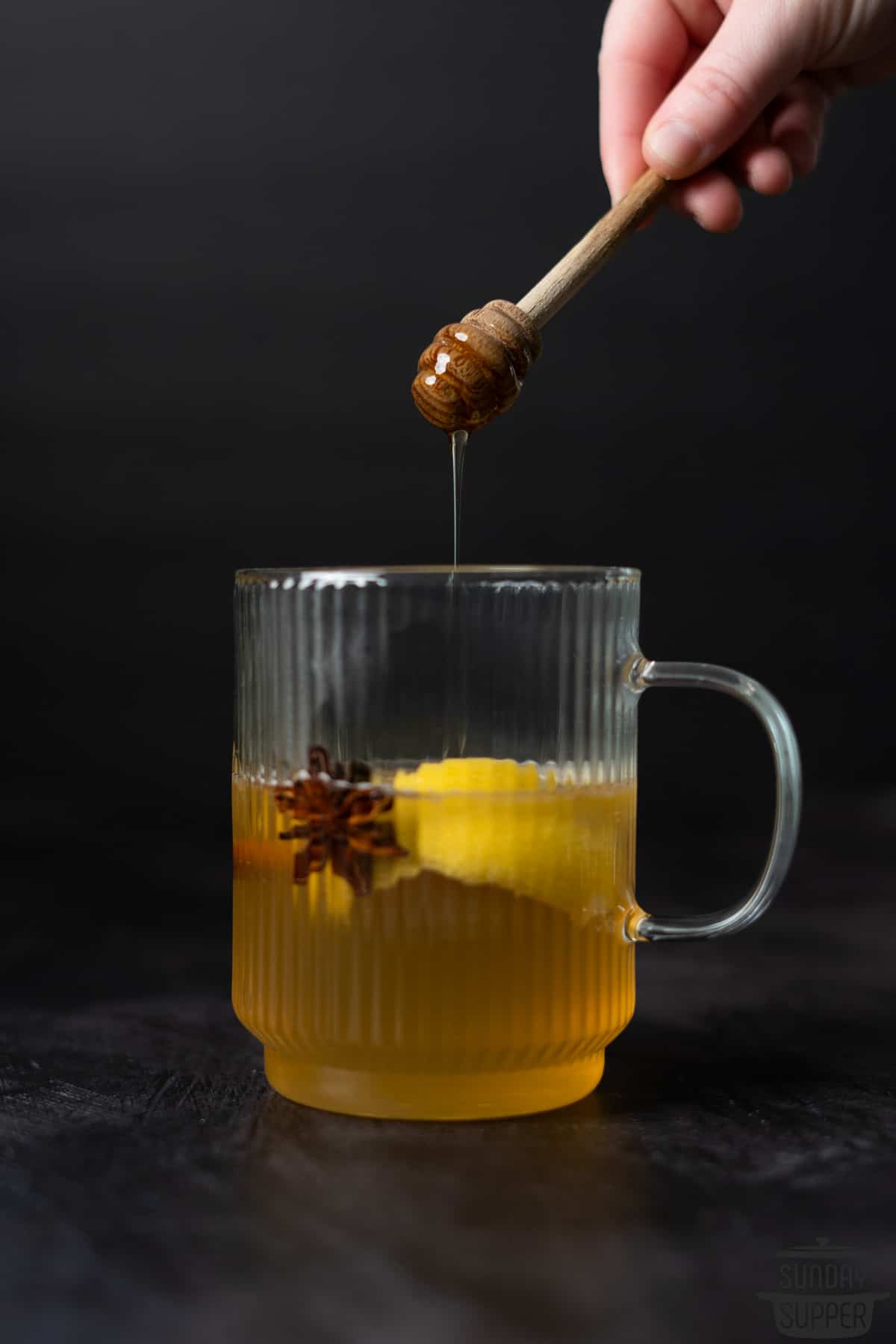 more honey being drizzled into a garnished hot toddy
