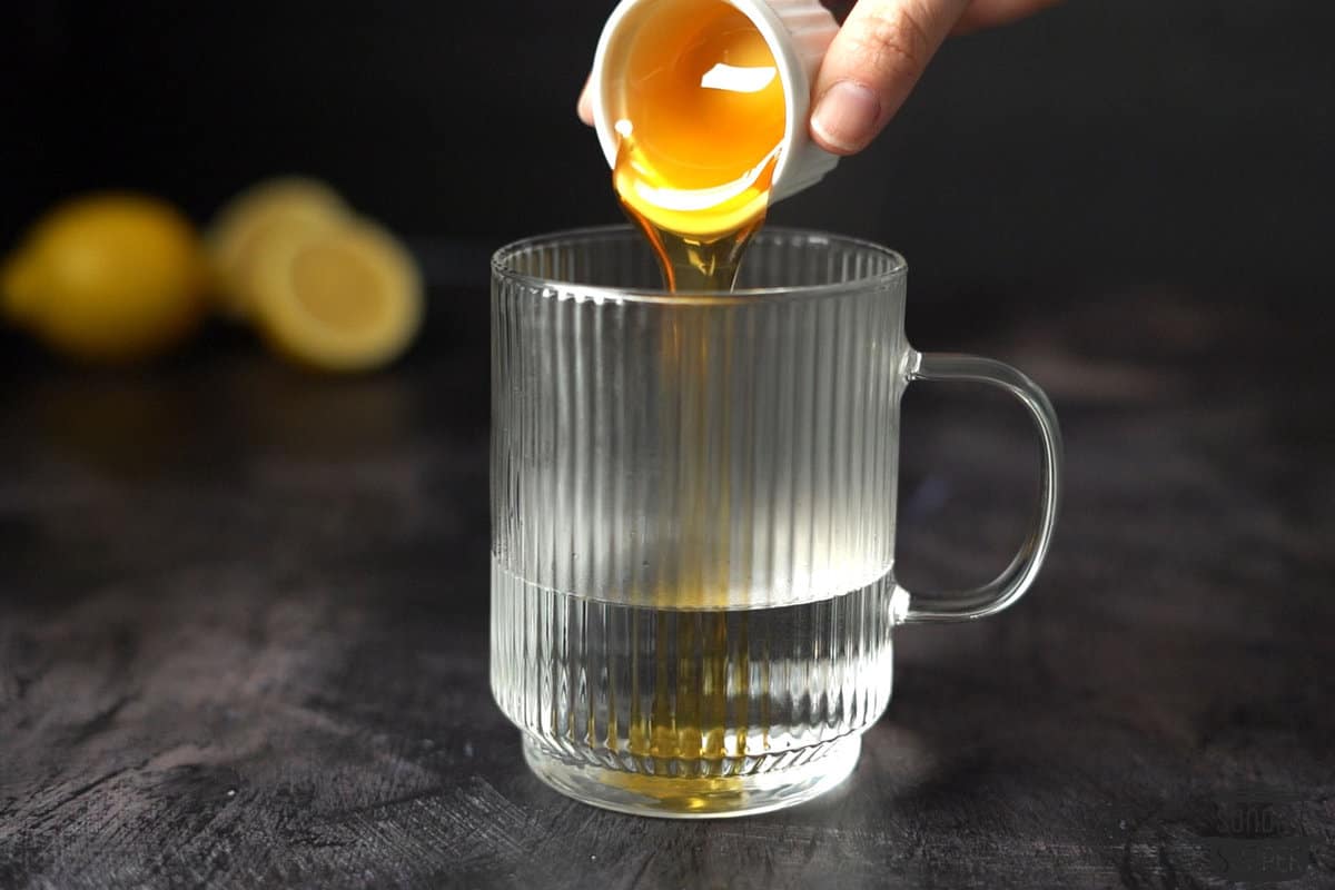 the honey being added to the mug of hot water