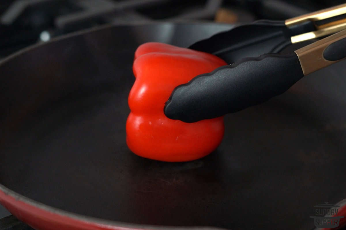 a pepper being held to a hot pan with tongs