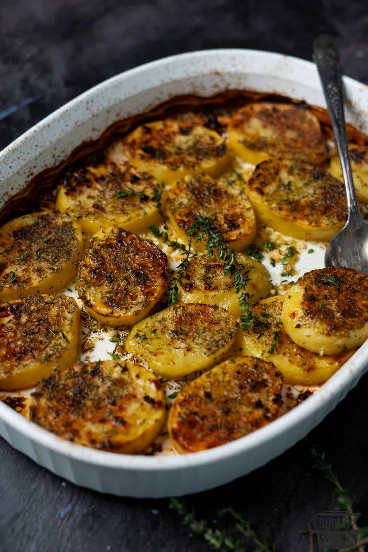baked and crispy melting potatoes in a pan with extra thyme