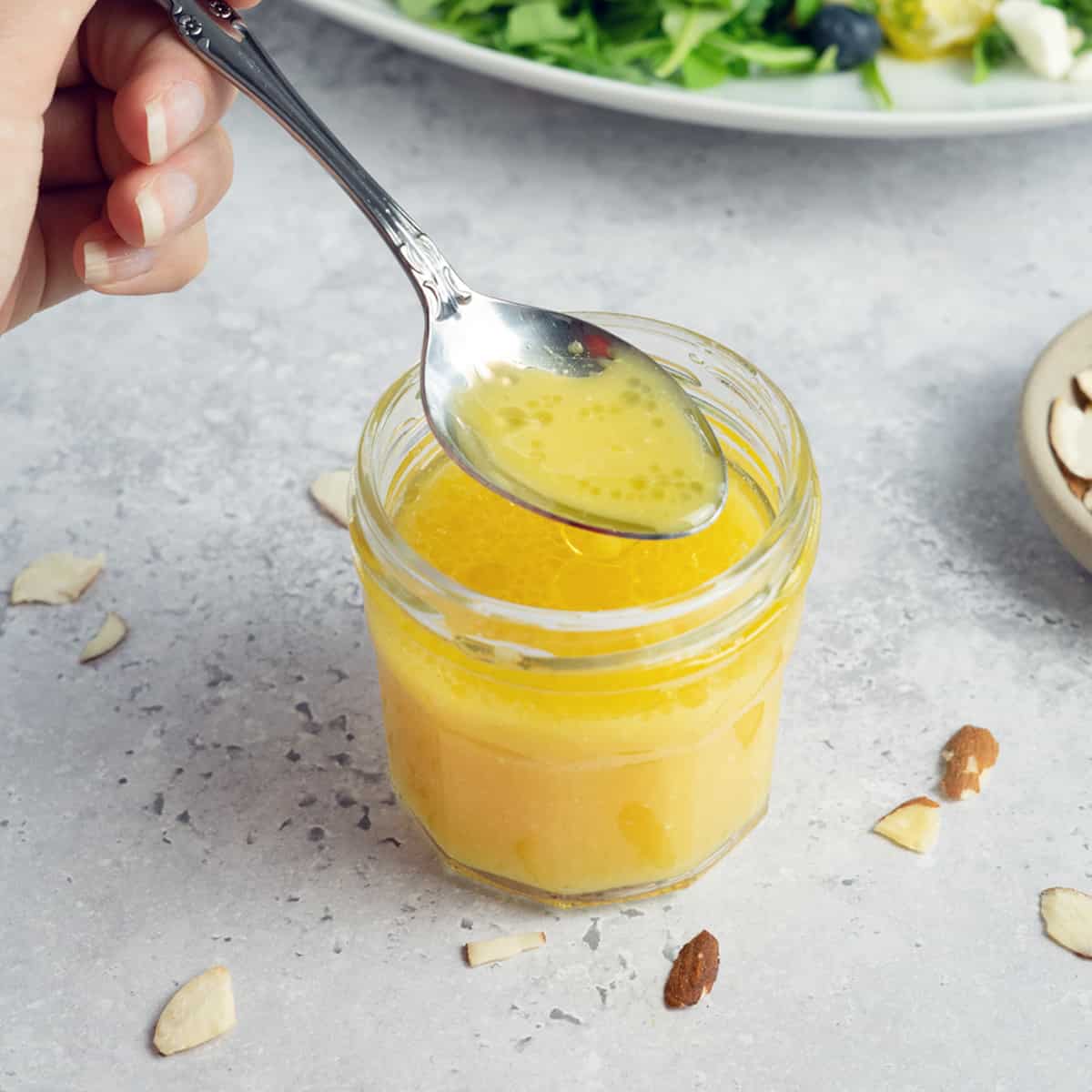 a spoon in a jar of orange dressing