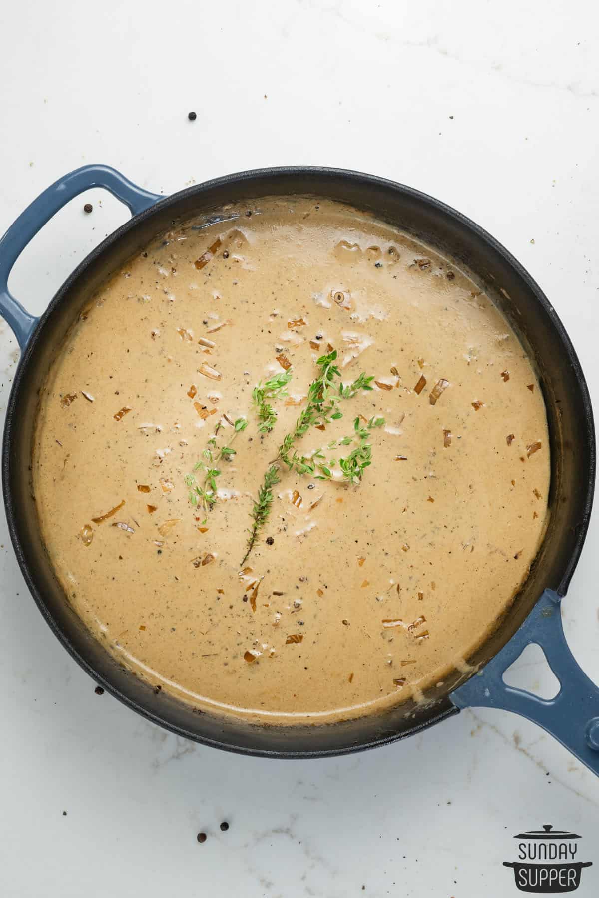 a pan of peppercorn sauce with sprigs of thyme added to the top