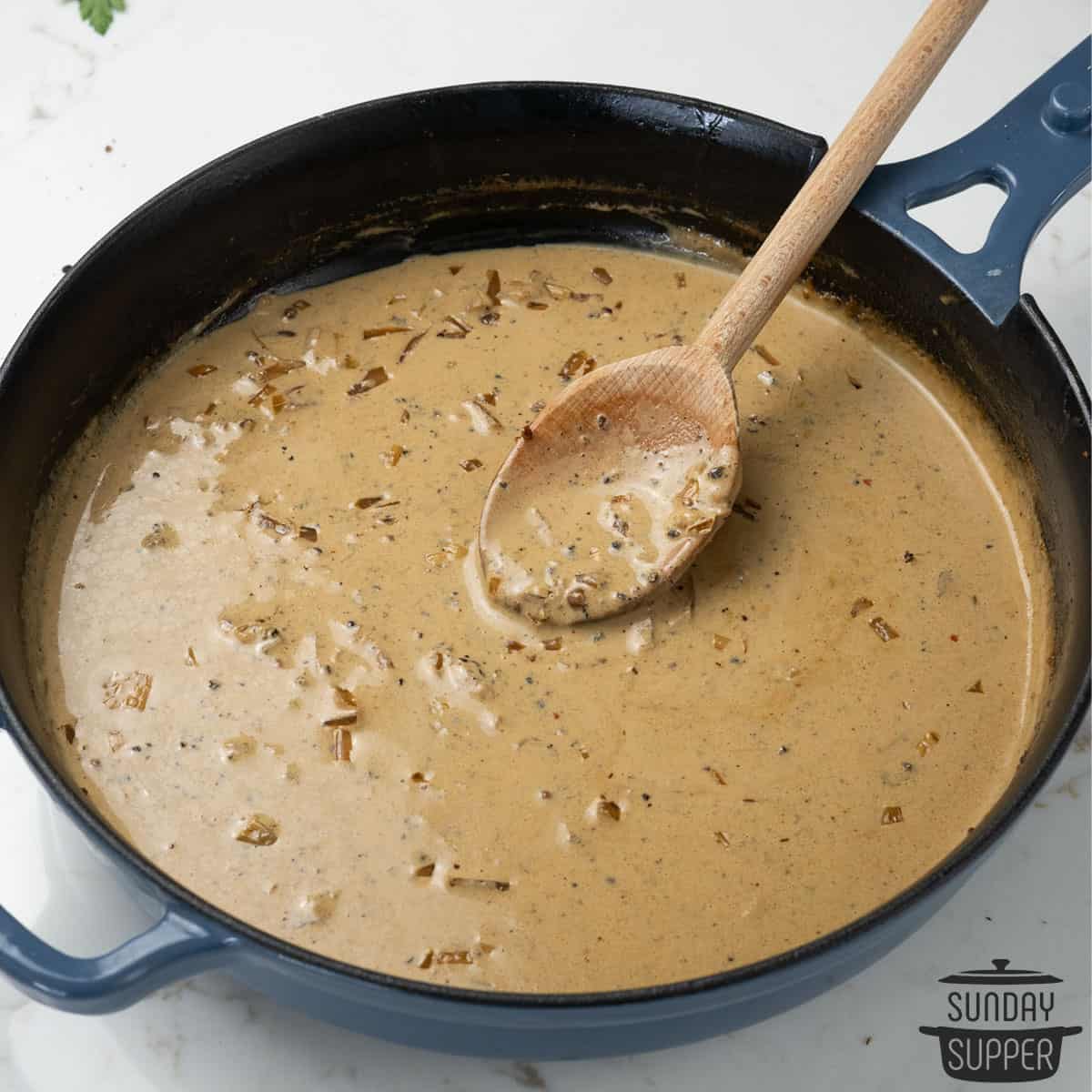 peppercorn sauce in a pan with a wooden spoon