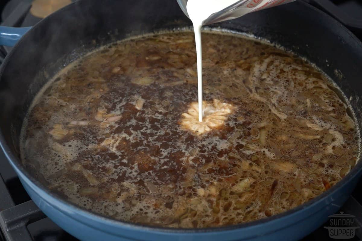 the cream being slowly poured into the pan of broth