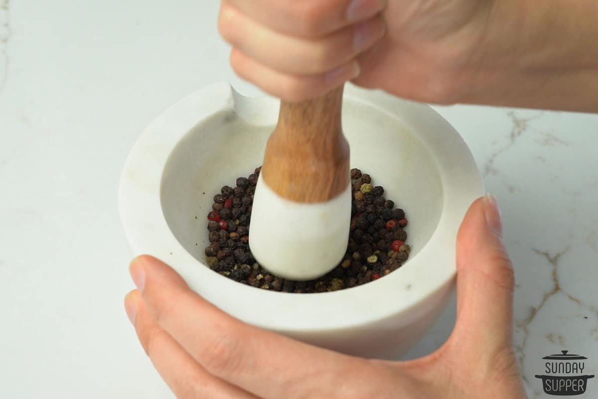 peppercorns being ground in a mortar with a pestle