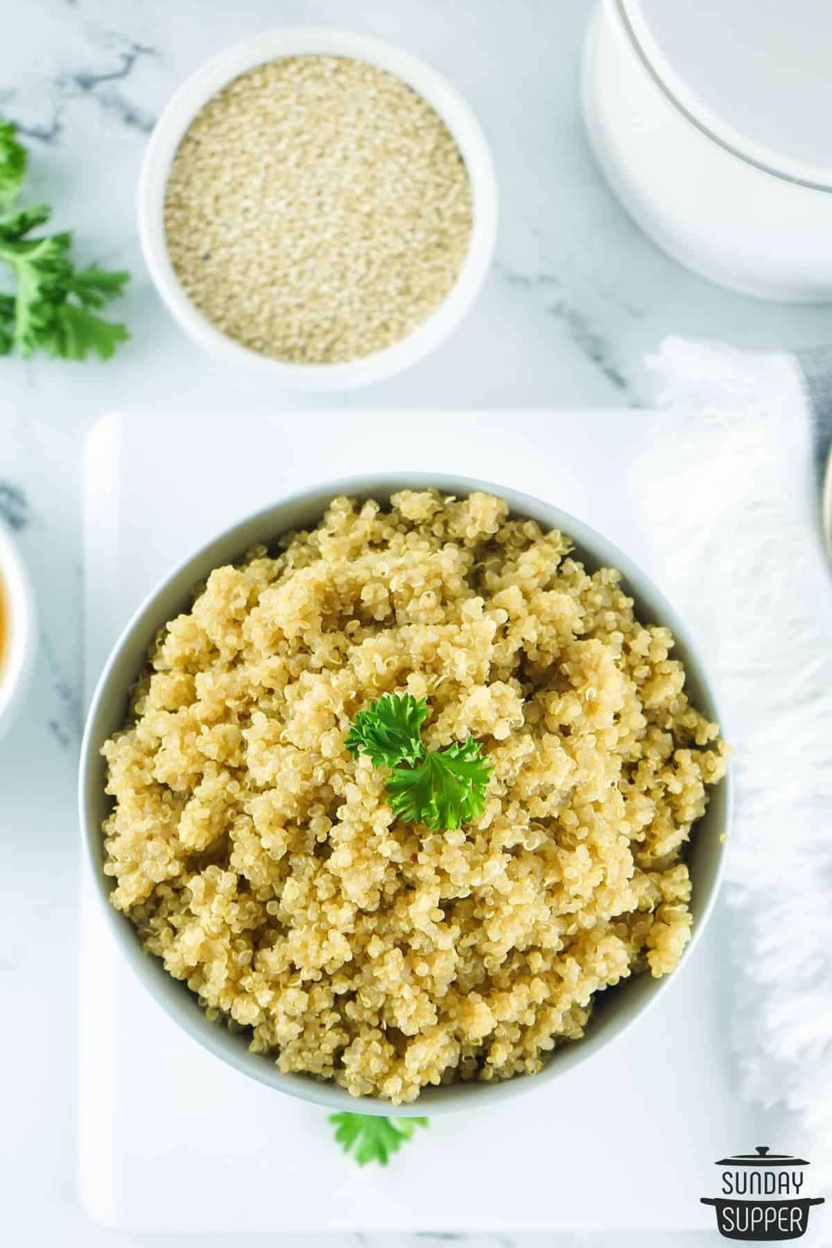 a bowl of fluffy quinoa next to a bowl of dry quinoa