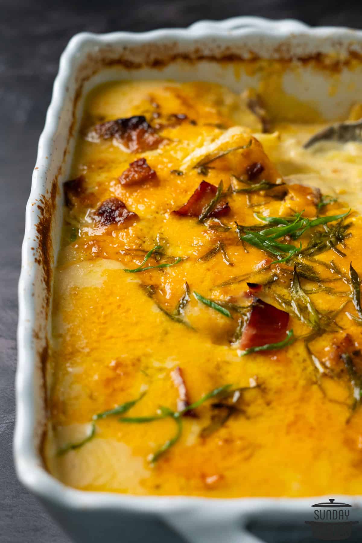 scalloped potatoes with ham in a casserole dish with extra herbs