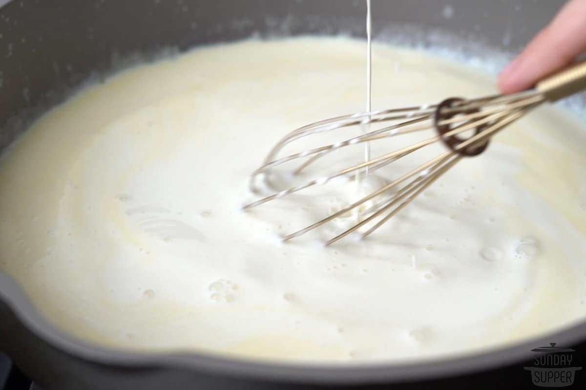 the milk and cream being slowly added to the butter and flour