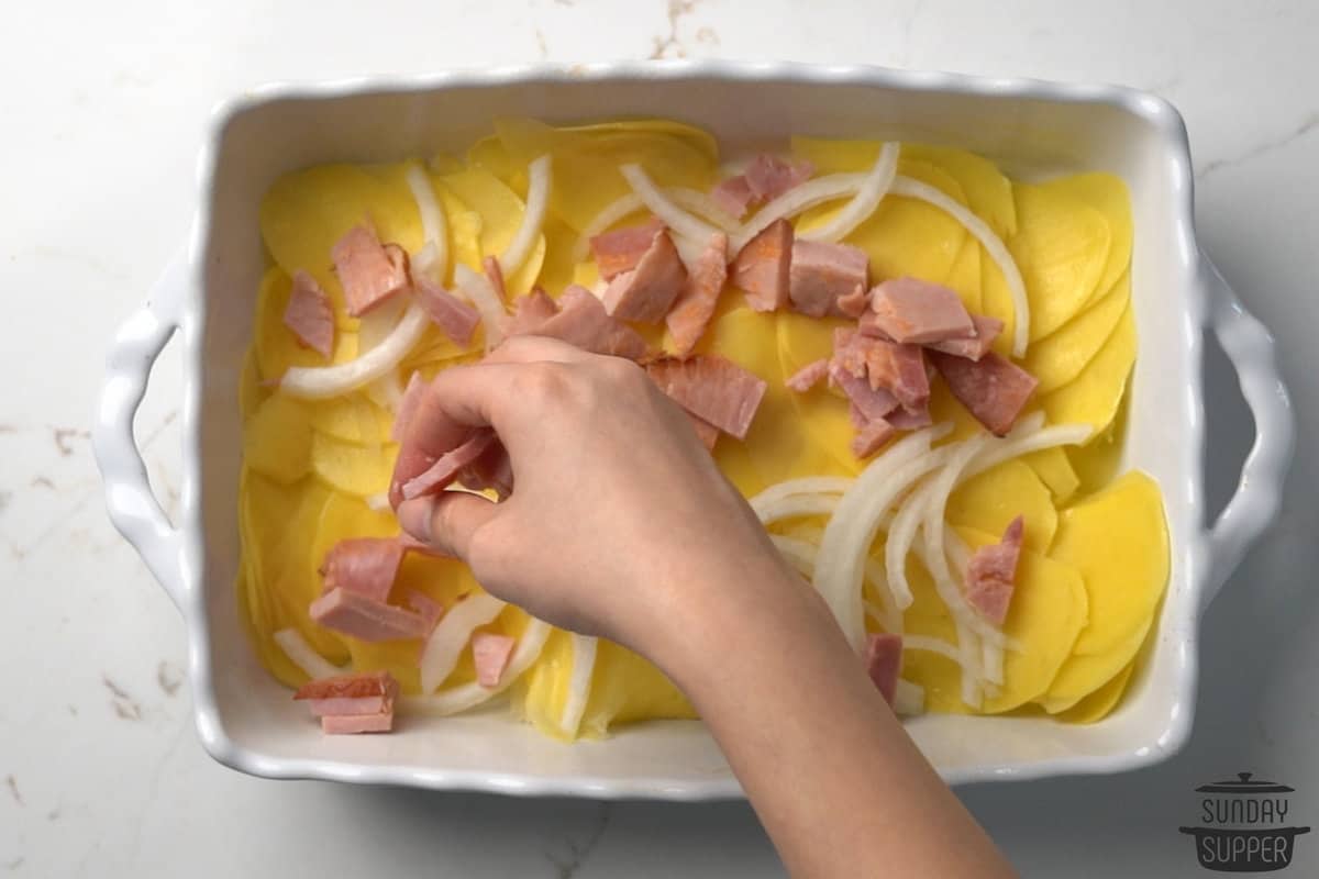 potatoes, onions, and ham layered in a casserole dish