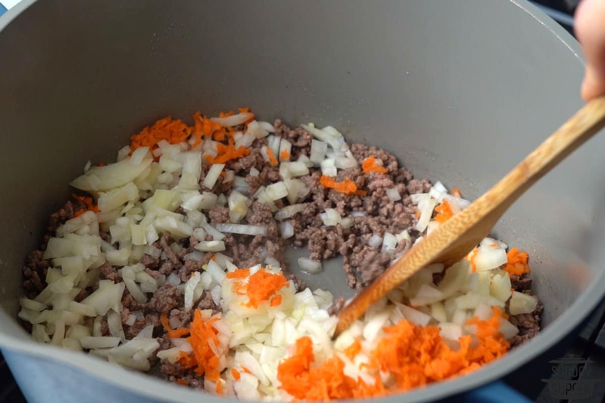 mixing ground beef with onions and carrots