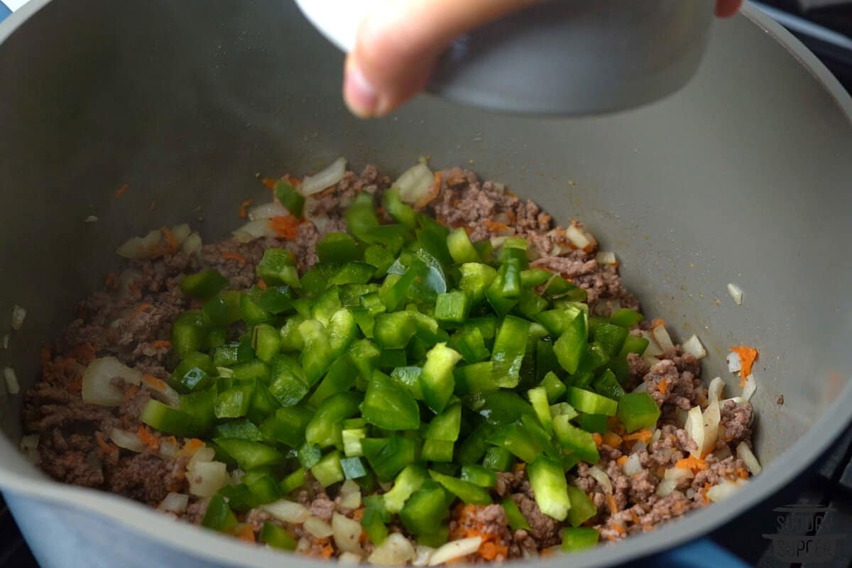 adding bell peppers to pot with ground beef mixture